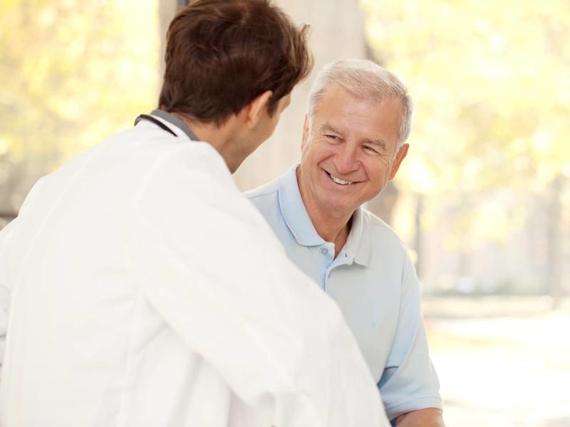 elderly male smiling while speaking with a doctor