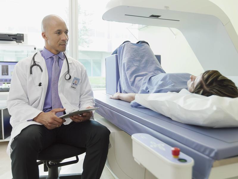 patient laying inside a bone density machine with physician next to them