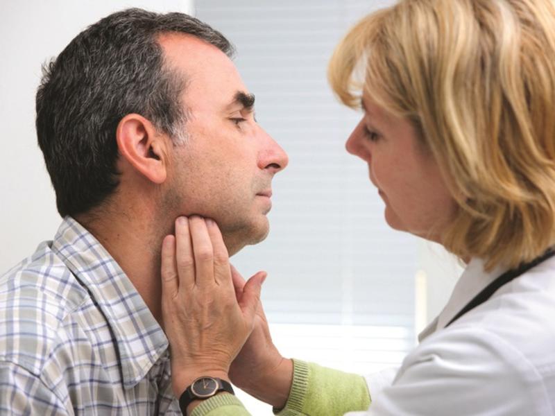 Woman doctor examining neck of patient.