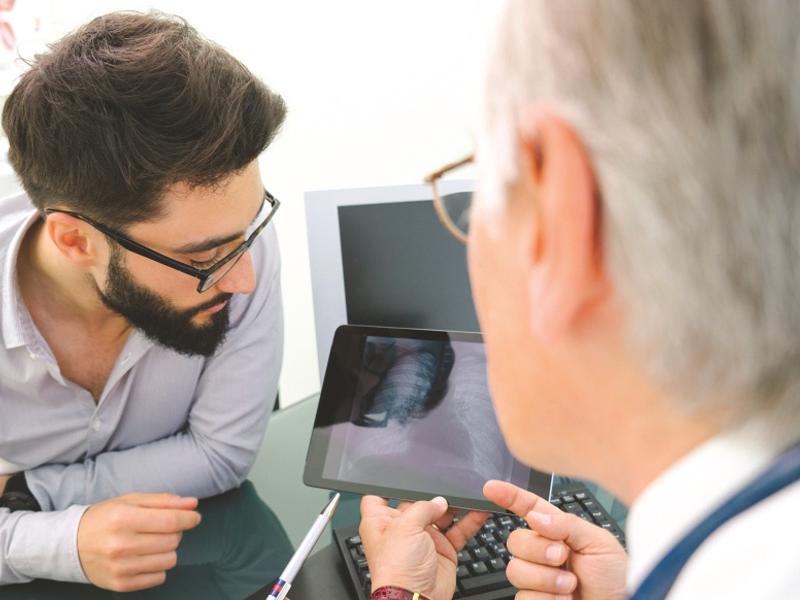 Doctor showing patient image of lung on tablet.