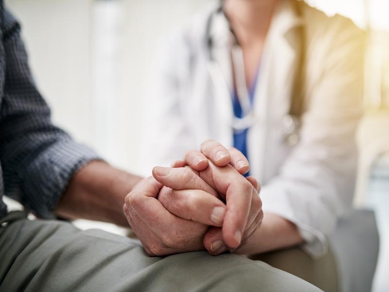 Health care provider holding patient's hand.