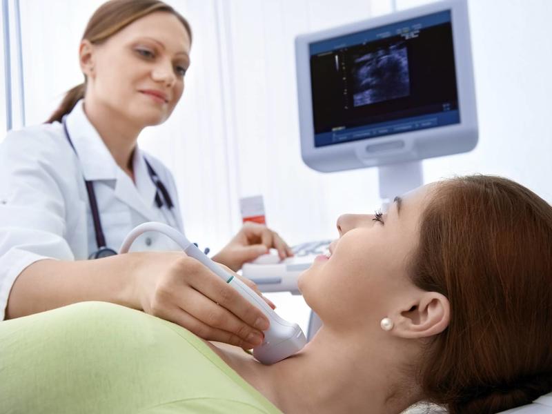 woman getting an ultrasound done on her neck by a technician