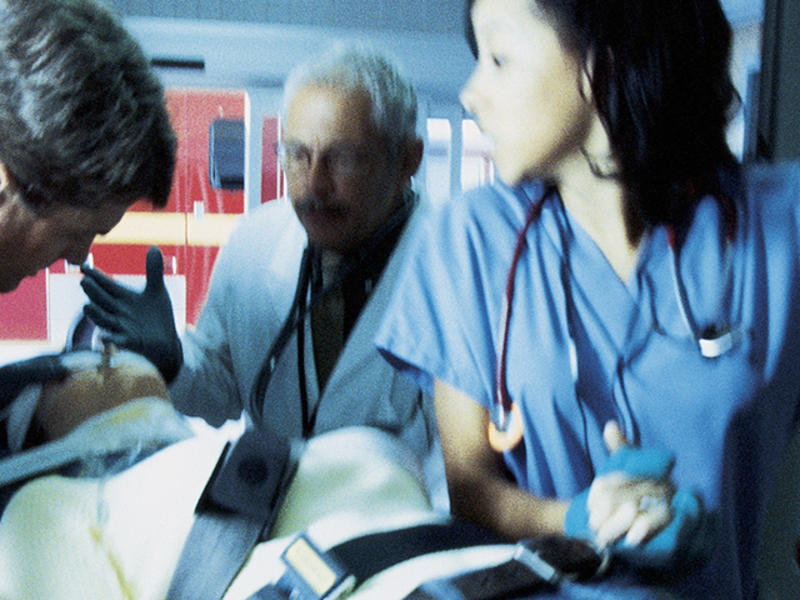 Three medical clinicians provide care to a patient on a gurney