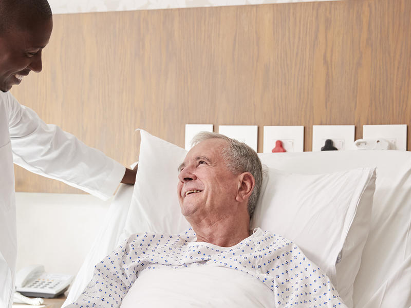 Doctor standing bedside speaking with patient in hospital room