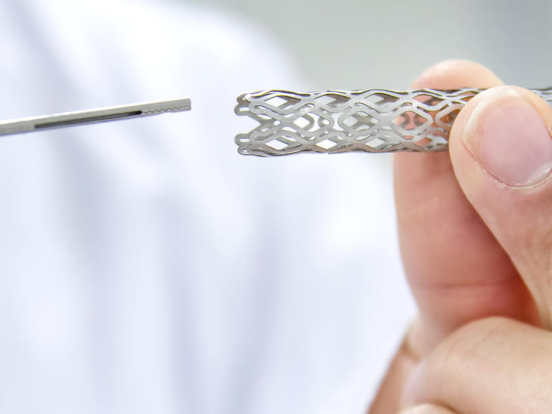 Doctor holds stent and thin wire-like medical device