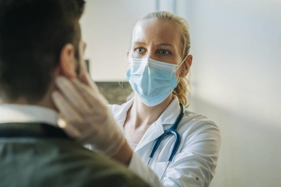 female physician examining a patient, while wearing a mask