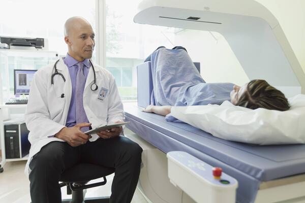 patient laying inside a bone density machine with physician next to them