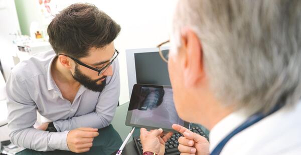 Doctor showing patient image of lung on tablet.