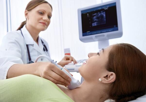 woman getting an ultrasound done on her neck by a technician