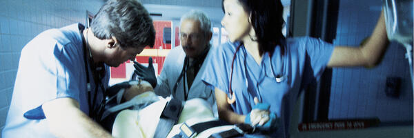 Three medical clinicians provide care to a patient on a gurney